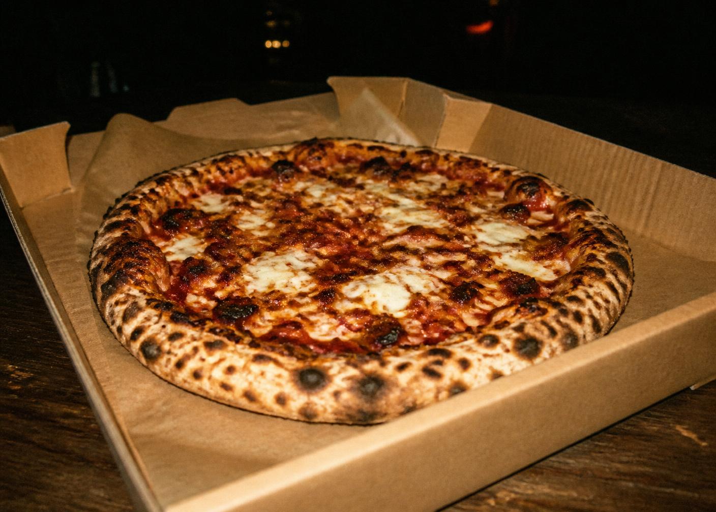 Charred sourdough pizza in a kraft box